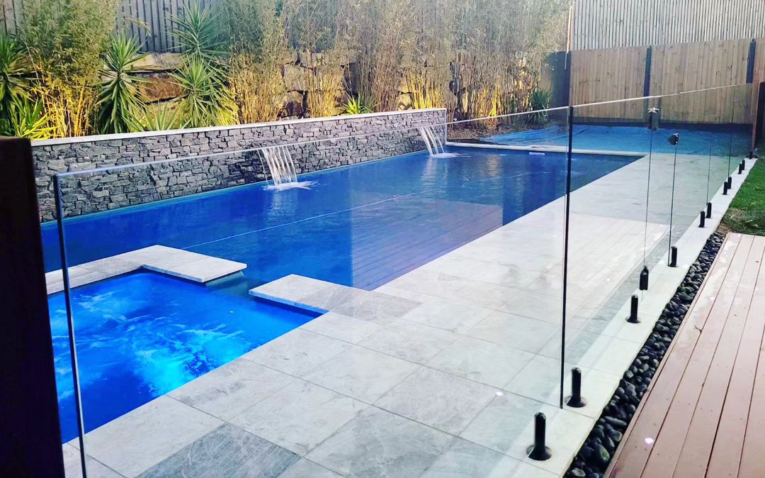 A backyard pool with a glass fence