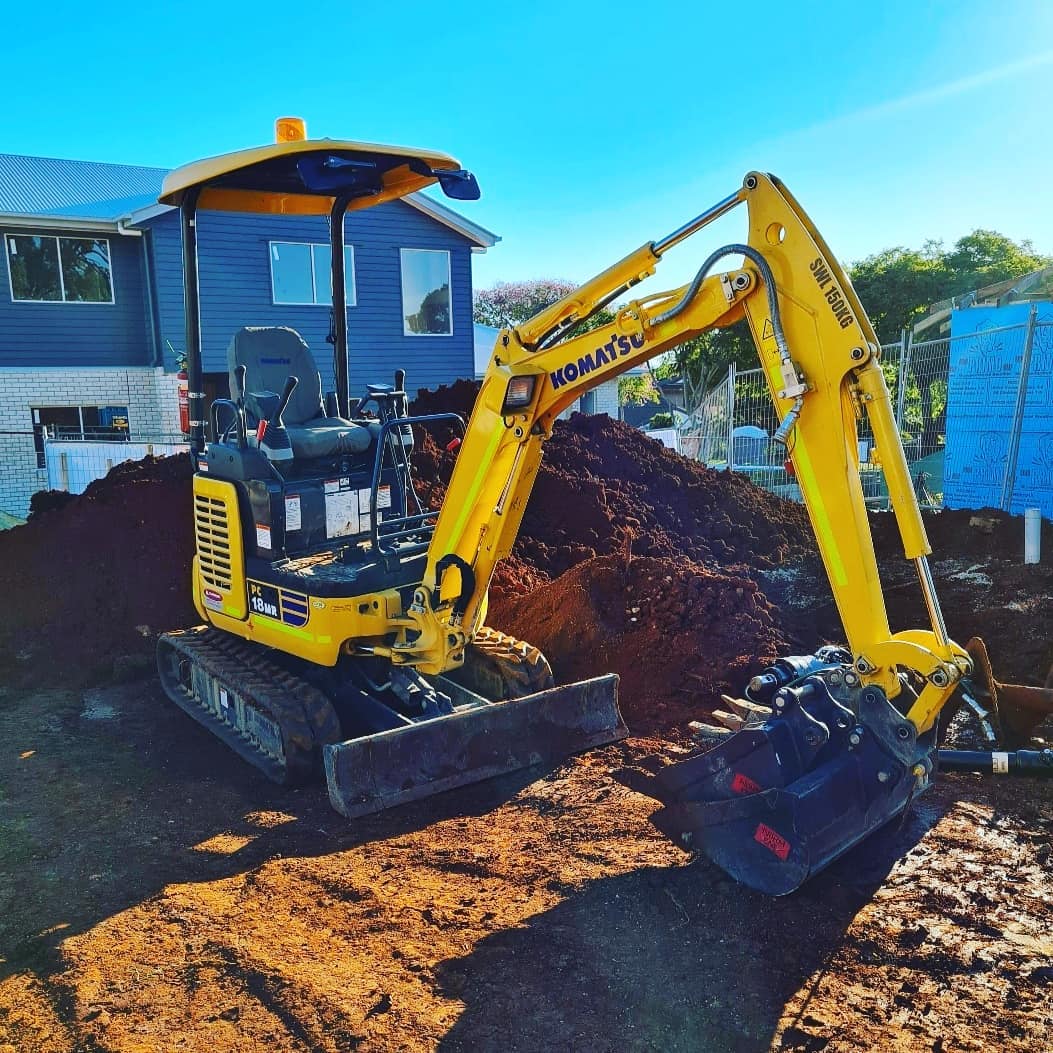 A yellow Komatsu digger in front of a dirt mound
