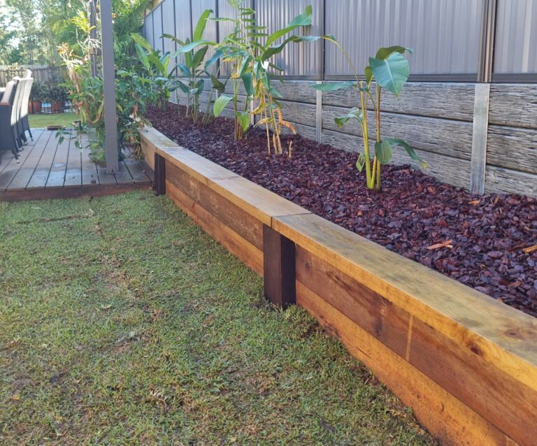 Pine sleeper retaining wall holding a garden bed with palm trees
