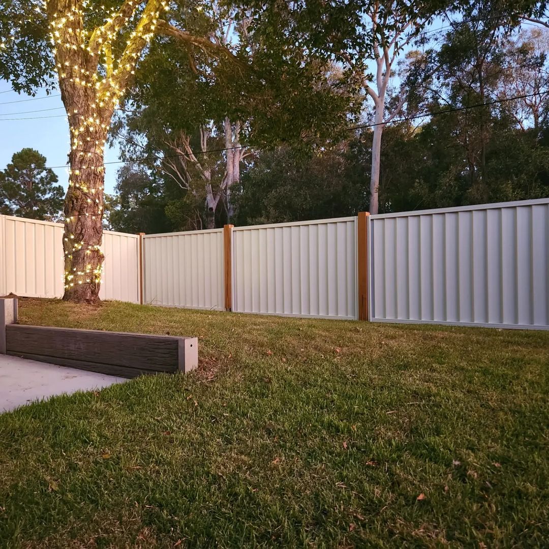 A white colorbond fence with timber posts
